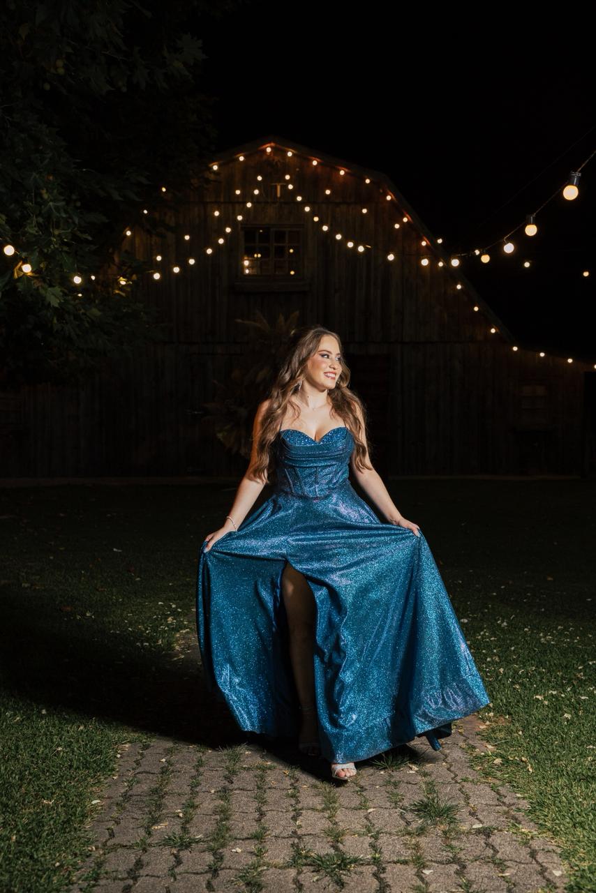 Formanda em vestido azul no celeiro iluminado