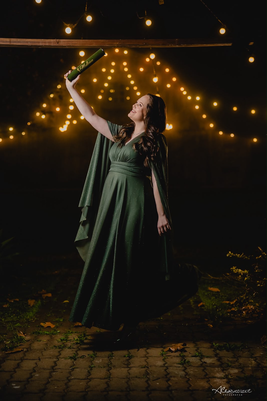 Formanda em vestido verde sob luzes decorativas